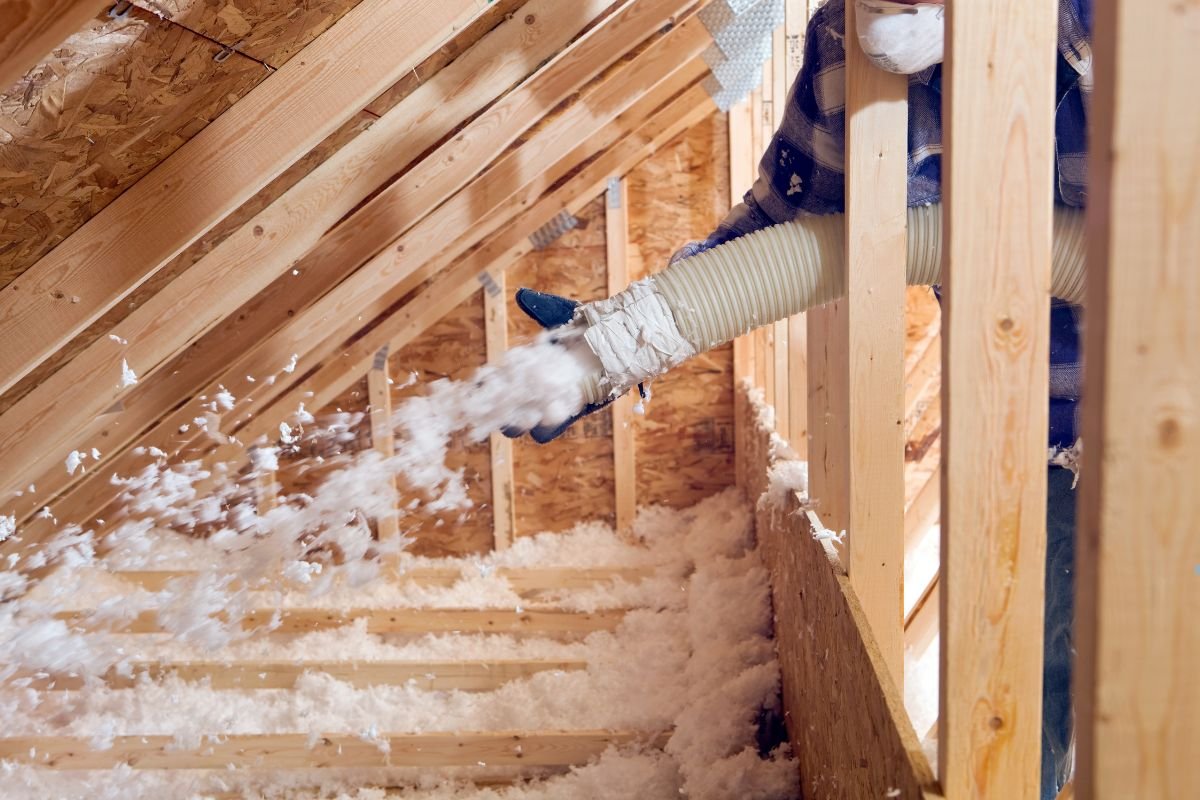 A man vacuums insulation from a home's interior, demonstrating a home improvement project. 