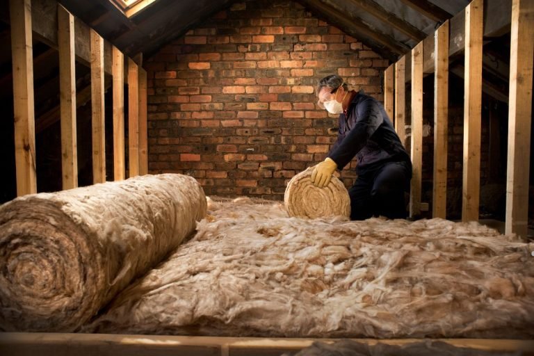 A man installs insulation in an attic, representing the services of the Best Insulation Company in Los Angeles.