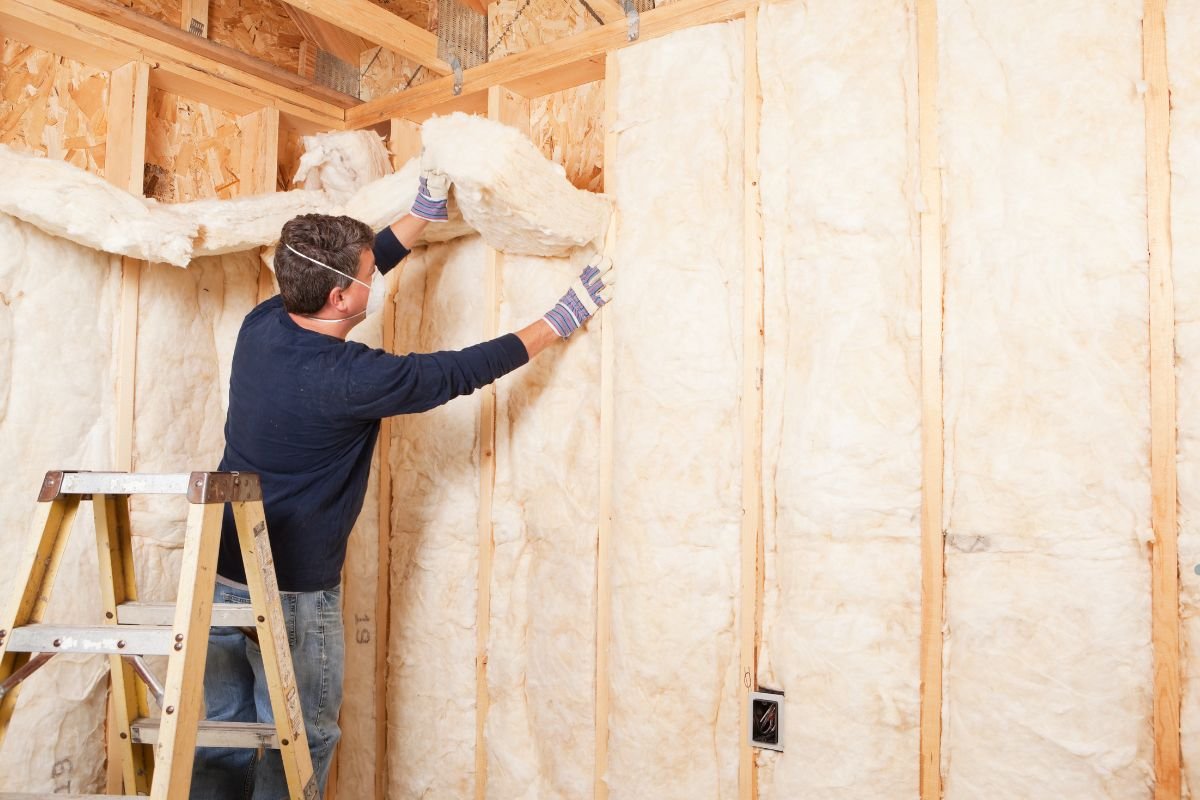 A man installs insulation in a room, enhancing the home's energy efficiency and comfort.